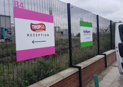 Industrial park wayfinding signs fixed to fencing outdoors