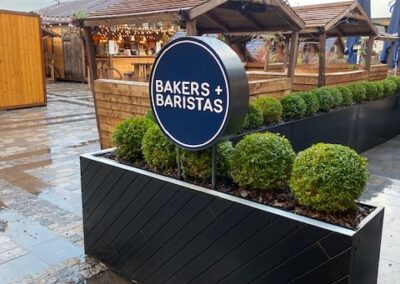 freestanding sign inside planter at Bakers & Baristas